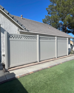A new light-colored vinyl privacy fence with a lattice top installed along a house by 702 Fence LLC in Las Vegas, NV.