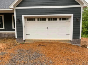 A newly installed white carriage-style garage door on a house under construction by CHS Garage Repair of Seattle, WA.