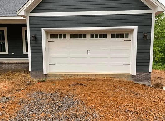 A newly installed white carriage-style garage door on a house under construction by CHS Garage Repair of Seattle, WA.