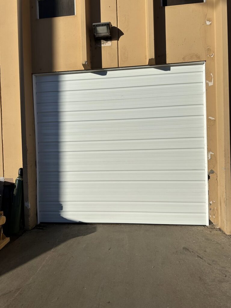 A newly installed white commercial garage door by Strongdoor garage in Denver, CO.