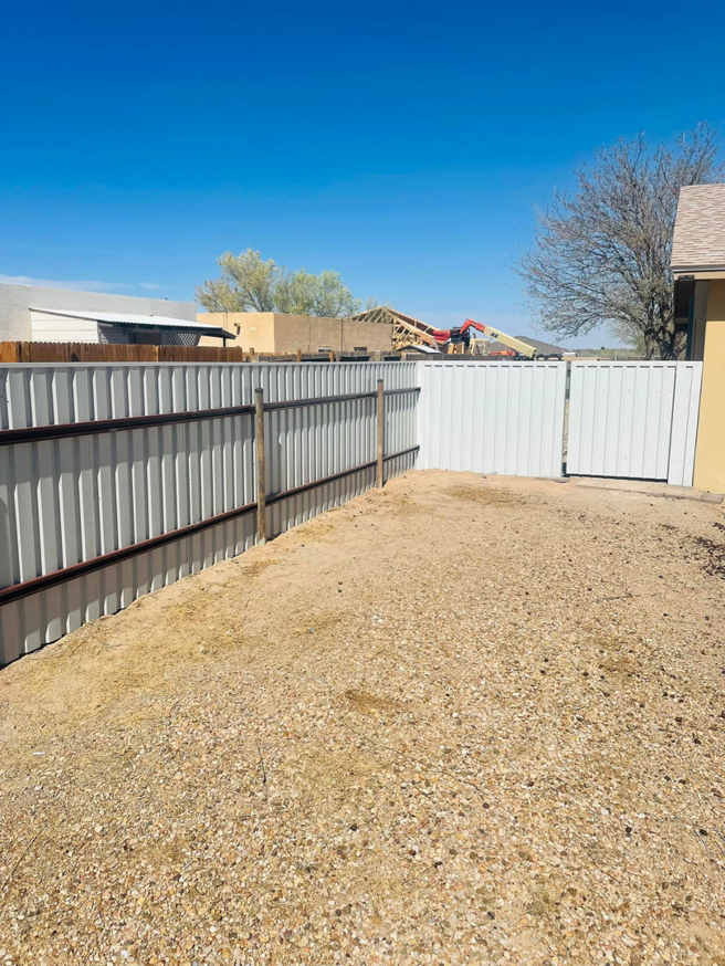 A long stretch of newly installed white corrugated metal fence by Pecos Construction and Fencing, LLC in Roswell, NM.
