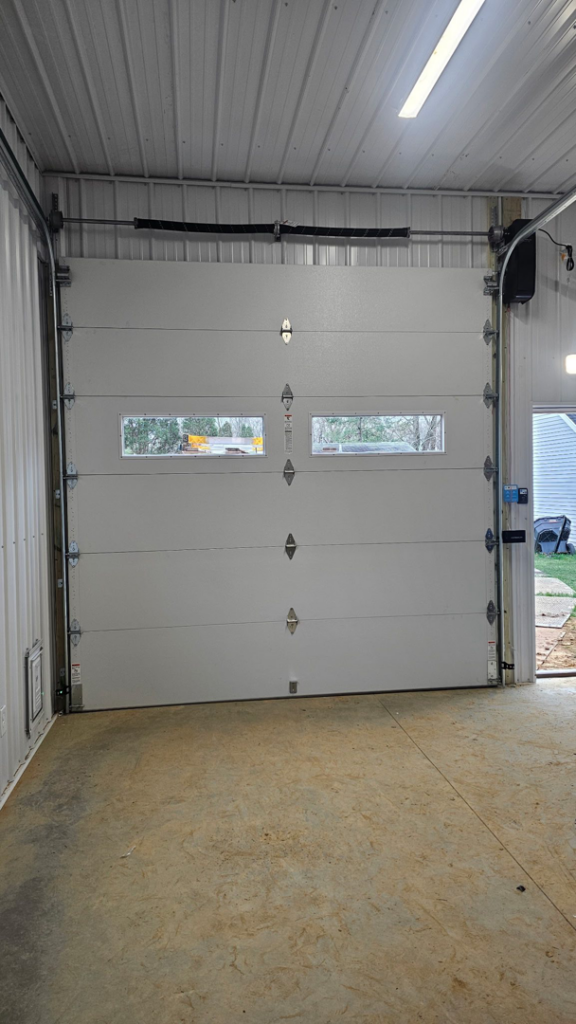 A newly installed white garage door with windows and opener mechanism by A+ Garage Door Repair in Evansville, IN.
