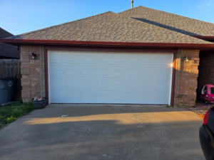 A newly installed white panel garage door on a brick house by APEX Garage Doors and Carports in Lawton, OK.