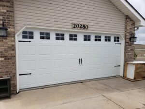 A newly installed white garage door with windows and decorative hardware by Black Forest Door Repair in Colorado Springs, CO.