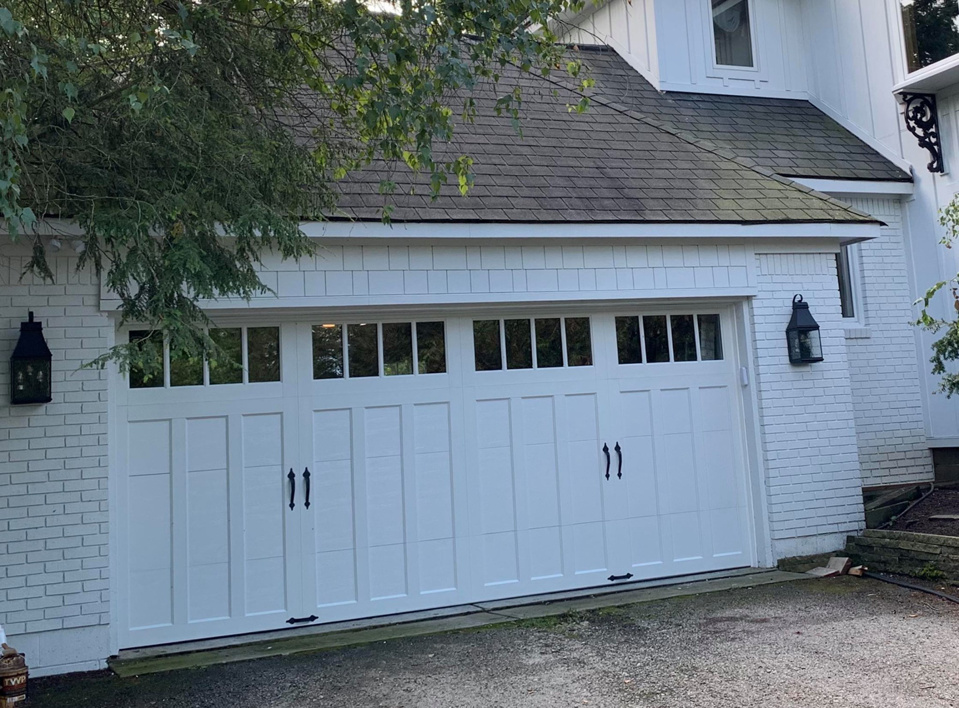 A newly installed white garage door with windows and decorative handles by C&D Door Service, Hamilton County Garage Doors in Noblesville, IN.