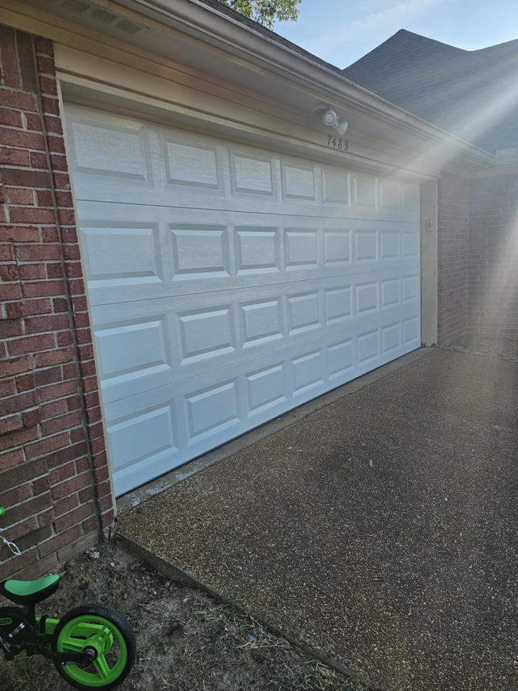 A newly installed white garage door on a brick home by The Garage Man in Memphis, TN.