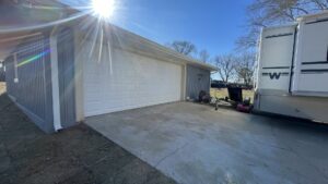 A new white garage door installed on a light blue sided garage by The Birmingham Man Garage Doors in Birmingham, AL.