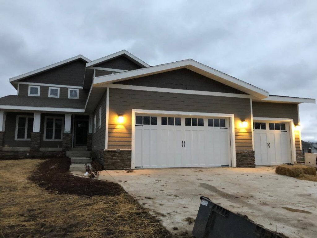 Two new white garage doors with decorative hardware on a modern residential home, installed by Madison Overhead Garage Door Services in Madison, WI.