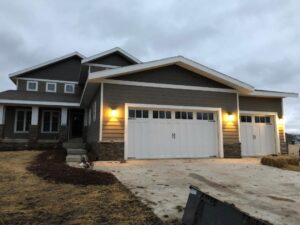 Two new white garage doors with decorative hardware on a modern residential home, installed by Madison Overhead Garage Door Services in Madison, WI.
