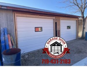 Two newly installed white garage doors on an outbuilding by Garage Door Repair Company, LLC in Pueblo, CO.