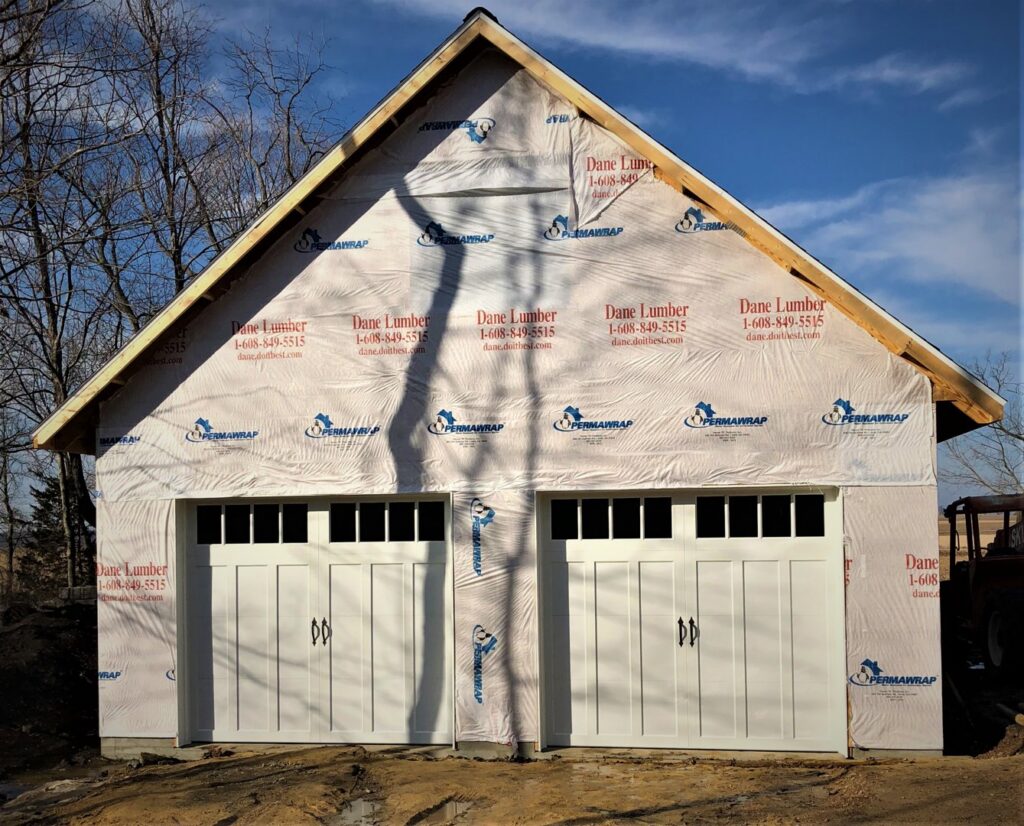 Two new white garage doors installed on a house under construction, a project by Madison Overhead Garage Door Services in Madison, WI.