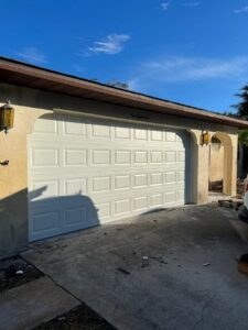 A new white panel garage door installed on a house, demonstrating work by Baystate Garage Door in Milton, MA.