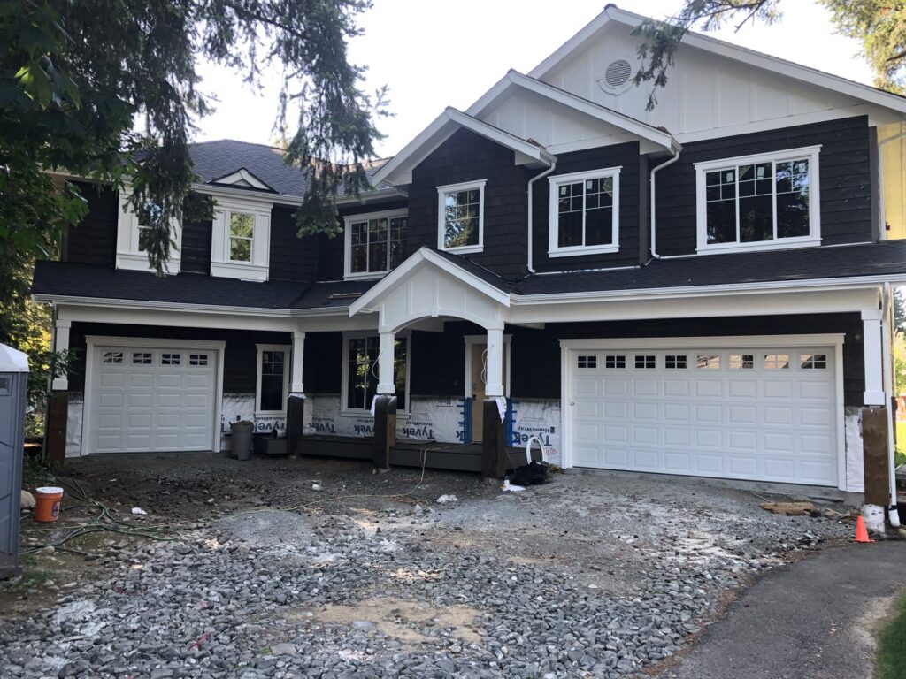 Installation of new white paneled garage doors on a new construction home by Steadfast Garage Door Services LLC in Federal Way, WA.