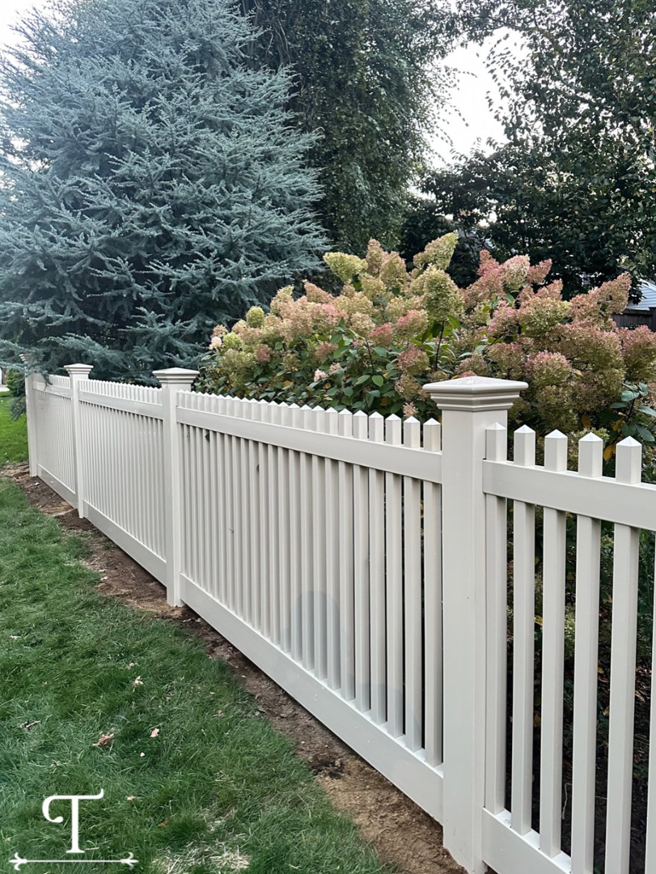 A new white picket fence installed along a property line by Teto's Fence Installation in Bridgeport, CT.