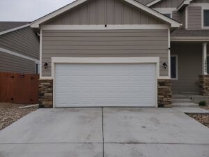 A newly installed white sectional garage door on a residential home by Black Forest Door Repair in Colorado Springs, CO.