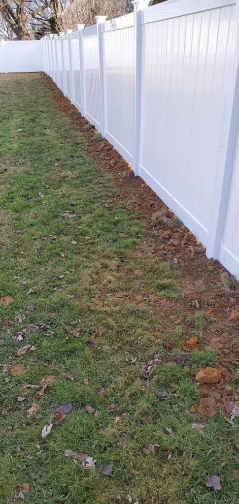 A newly installed white vinyl fence with fresh earth along its base by DZS Fencing, LLC in Red Lion, PA.