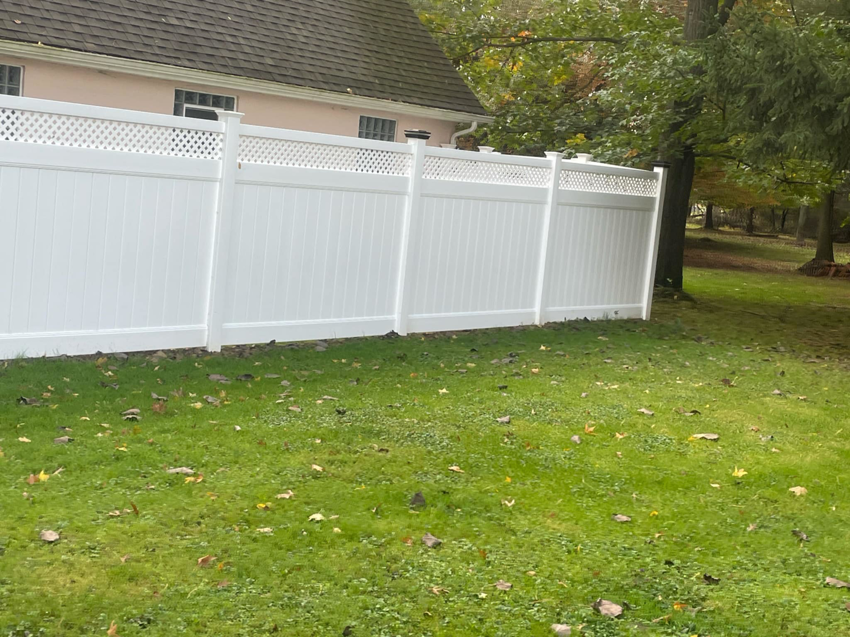 A newly installed white vinyl fence with a lattice top in a backyard by Fence Guys INC in Cleveland, OH.