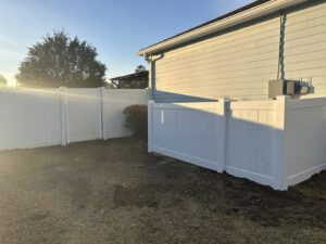A newly installed white vinyl fence enclosing a residential backyard by Gaines Fence in Jacksonville, FL.