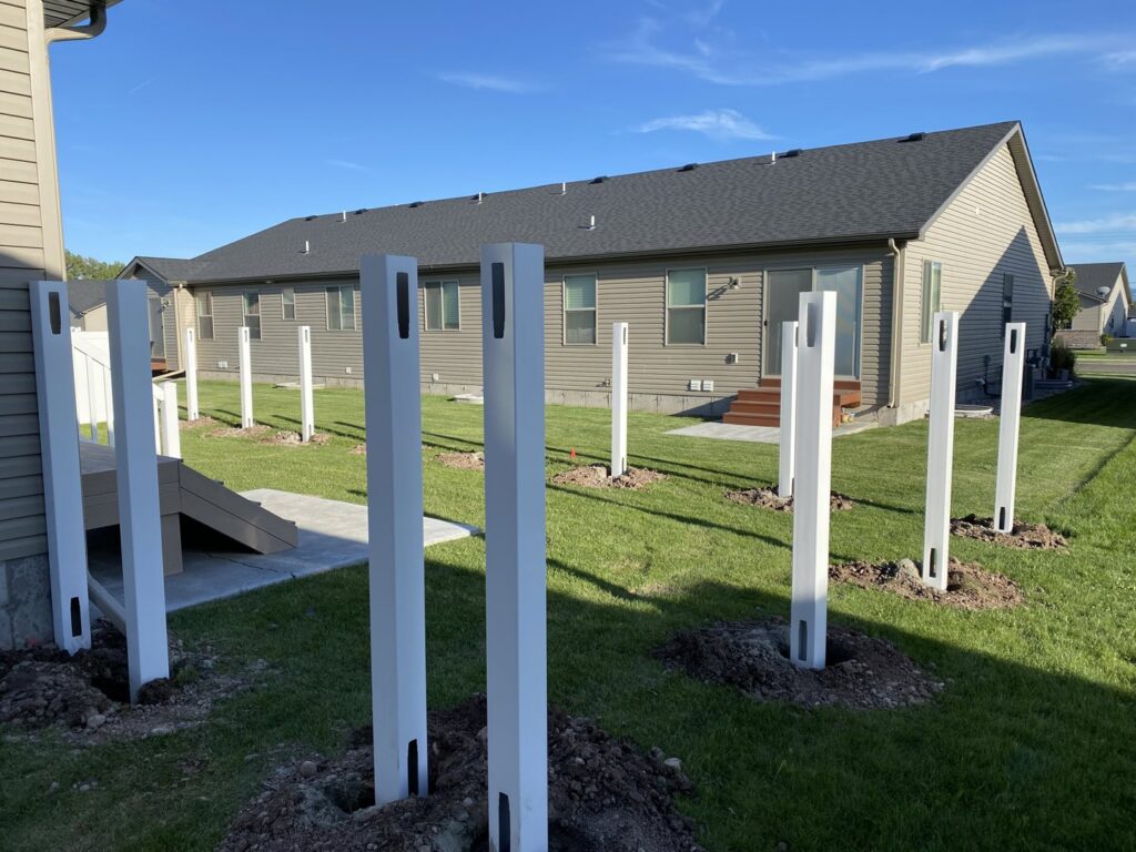 New white vinyl fence posts being installed in a residential backyard by Idaho Falls Fencing in Idaho Falls, ID.