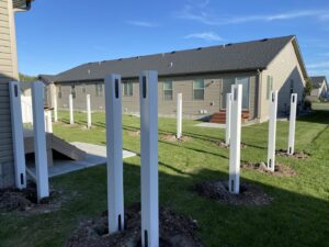 New white vinyl fence posts being installed in a residential backyard by Idaho Falls Fencing in Idaho Falls, ID.