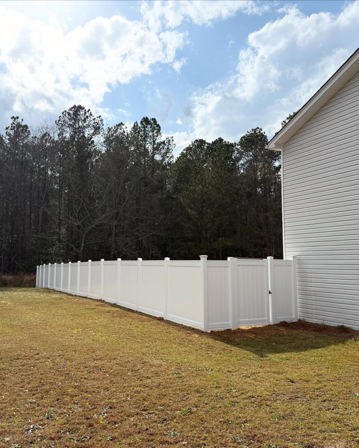 A newly installed white vinyl privacy fence next to a house by Brock Brothers Fence in Mobile, AL.