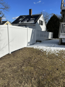 A new white vinyl privacy fence installed by Hunter & Sons Fence in Arlington, MA, bordering a residential property.