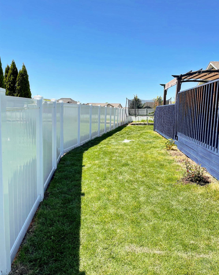 A newly installed white vinyl privacy fence in a residential backyard by RDU Fence in Holly Springs, NC.