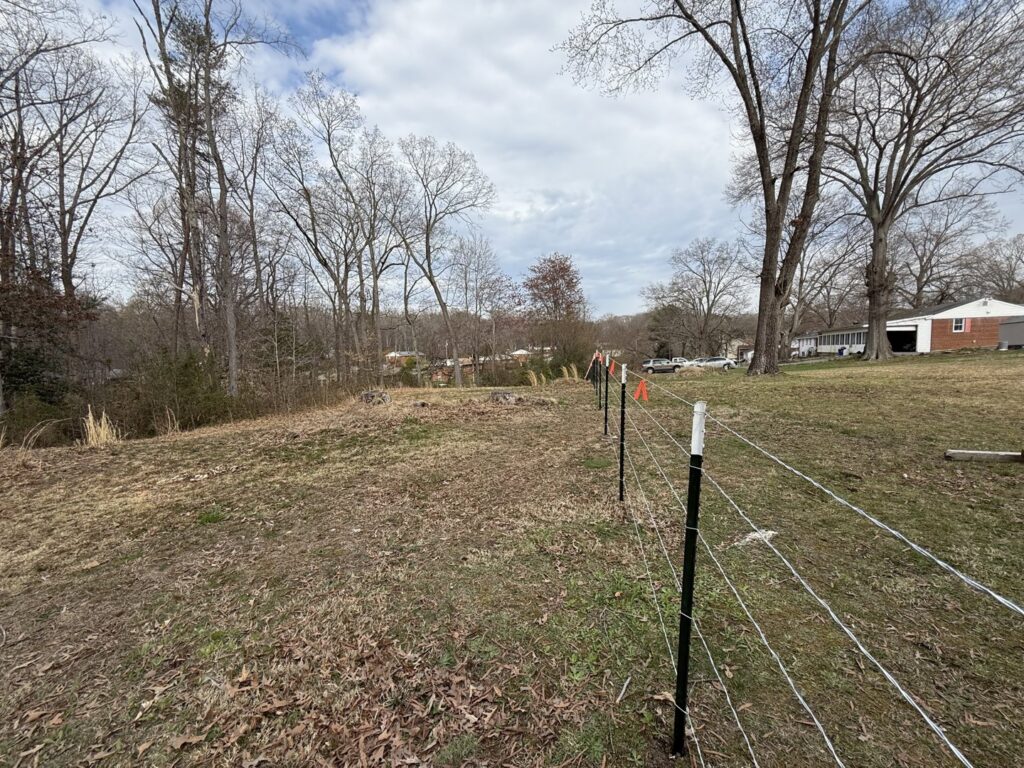A newly installed wire fence with metal T-posts in an open field, completed by AFK FENCE LLC in Waldorf, MD.