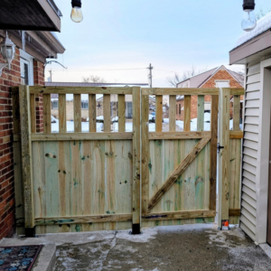 A newly installed wood double gate with a diagonal brace by Mjölnir Design, opening to a driveway in Milwaukee, WI.