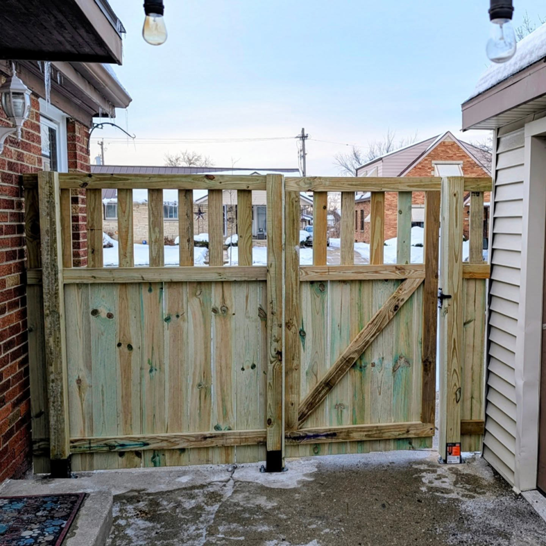 A newly installed wood double gate with a diagonal brace by Mjölnir Design, opening to a driveway in Milwaukee, WI.