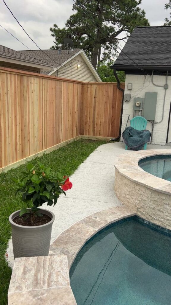 A new wood fence installed along a pool and concrete walkway by Wood Fence Houston in Houston, TX.