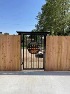 A new wood fence with a black metal gate featuring an OSU logo installed by Fence Restorations LLC in Ponca City, OK.
