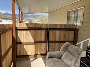 A newly installed wood fence with a double gate under a covered patio area by This And That Fence in Reno, NV.