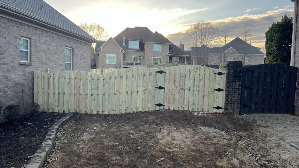 A new wood fence with a double gate installed by Precision Contracting LLC in Jupiter, FL, next to a brick pillar.