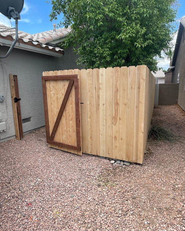 A newly installed wooden fence with a gate in a residential backyard by 702 Fence LLC in Las Vegas, NV.