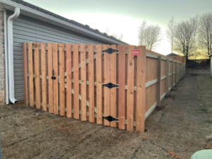 A newly installed wood fence gate featuring decorative black hardware by Best Fences LLC in Springdale, AR.