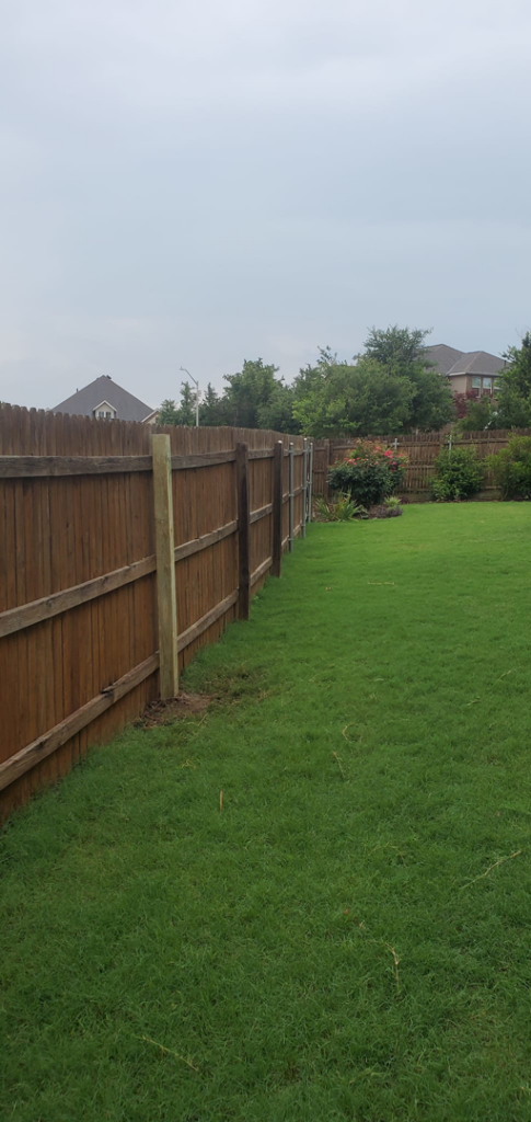 A newly installed long wooden fence line defining a backyard space by T&G Outdoor Services in Austin, TX.