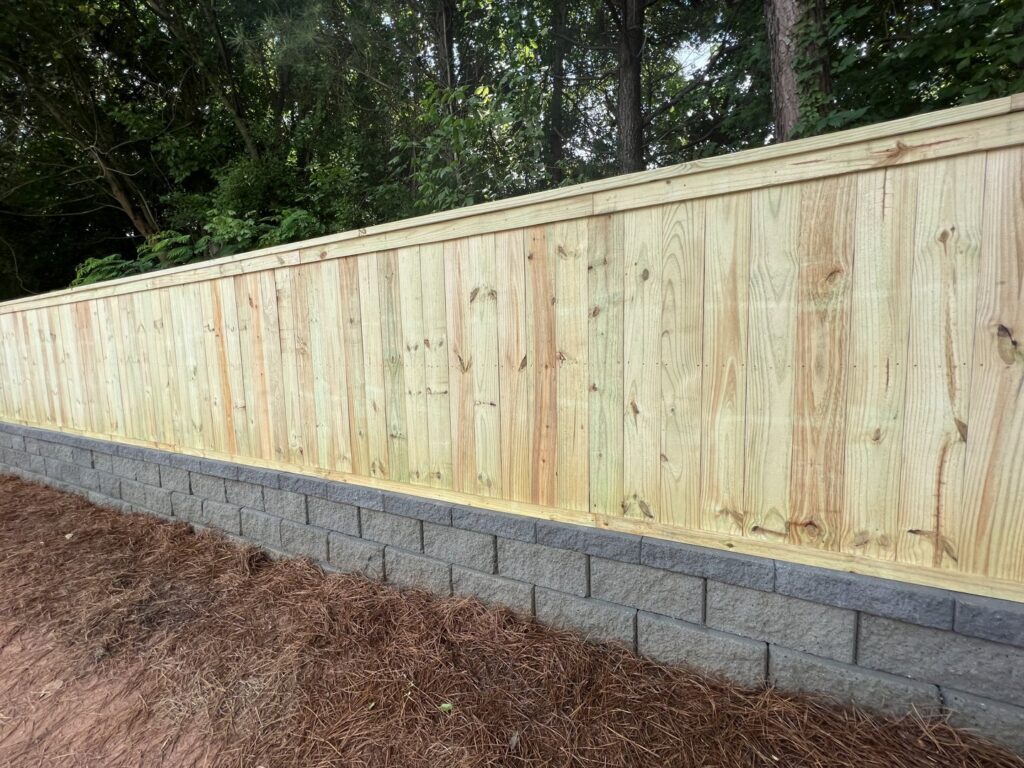 A new wood fence installed on top of a stone retaining wall by 3A Fencing & Landscaping in Atlanta, GA.