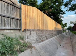 A newly installed wood fence on top of a stone retaining wall by DWM FENCE in Norman, OK