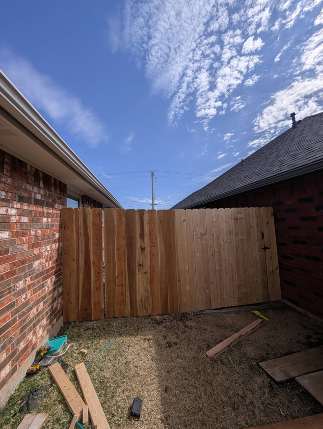 A newly installed wood fence section and prepared gate area by Black and Sons fencing in Indiahoma, OK.