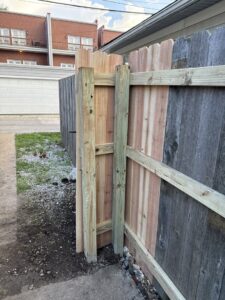 A new wood fence section being installed, showing fresh lumber next to an older fence by Exterior Experience LLC in St. Louis, MO.