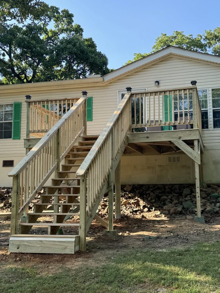 A newly installed wood fence section next to an existing metal fence, with a decorative birdhouse, by Faithful Fencing LLC in Batesville, AR.