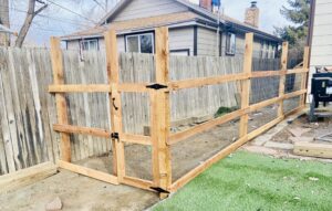 A newly installed wooden fence with wire mesh and a gate by 2 Guys & A Girl Lawn Care in Thornton, CO.
