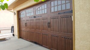 A newly installed wood-grain carriage style garage door with decorative windows and hardware by Mountain Fox Garage Doors in Colorado Springs, CO.