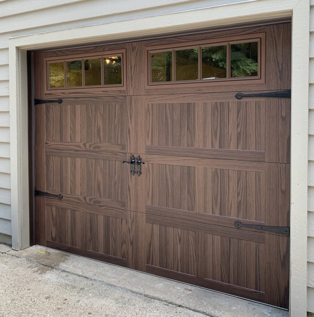 A newly installed wood-grain style garage door with decorative windows and hardware by Affordable Overhead Garage Door in Modesto, CA