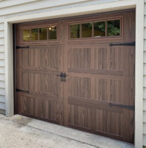 A newly installed wood-grain style garage door with decorative windows and hardware by Affordable Overhead Garage Door in Modesto, CA