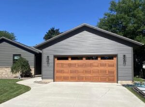 A new wood-look garage door installed on a residential house, showcasing a completed project by Overhead Doors Unlimited, LLC in Appleton, WI.