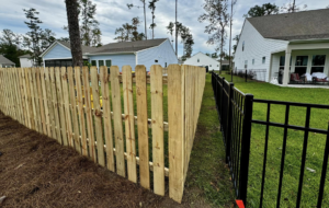 A new wooden picket fence alongside a black metal fence, showcasing work by Barwick Fence Company in Savannah, GA.