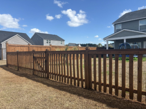 A newly installed wood picket fence with a gate in a residential backyard by Stain and Go in Summerville, SC.