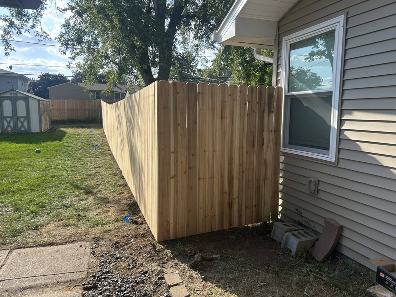 A new wood picket fence installed along the side of a residential house by Walker Fence in Council Bluffs, IA.